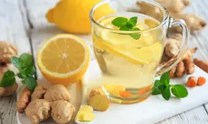 Napój z cytryną, imbirem i miętą wspiera rekonwalescencję. Na stole leżą cytryny, imbir i świeża mięta.