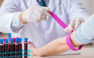 Pobieranie krwi do badań. Lekarz w rękawiczkach zakłada opaskę uciskową, by sprawdzić, czy eozynofile niskie nie są przyczyną problemów.
