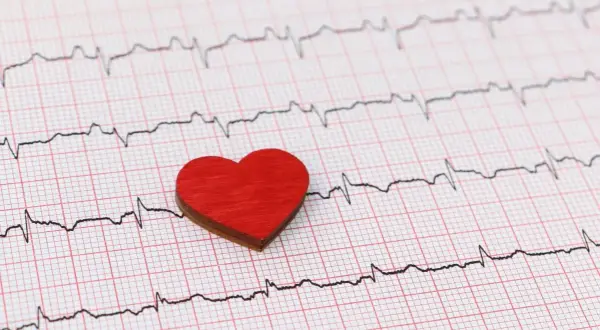 Czerwone serduszko na tle zapisu EKG. Może symbolizować troskę o serce i świadomość objawów wysokiego ciśnienia.