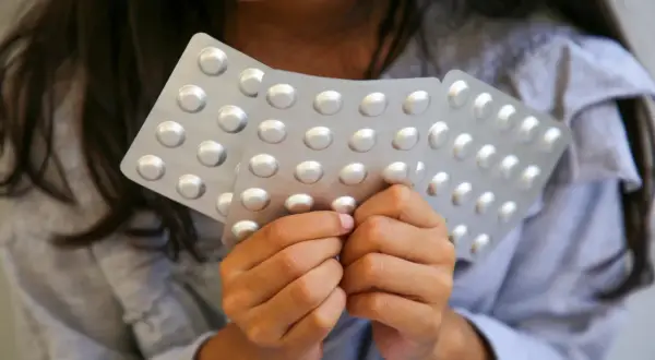 Dziecko trzyma blistry z tabletkami, być może z lekiem takim jak Ritalin.