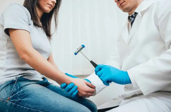 Neurolog bada odruchy pacjentki młoteczkiem neurologicznym.